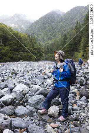 A woman climbing a mountain wearing a raincoat 118453669