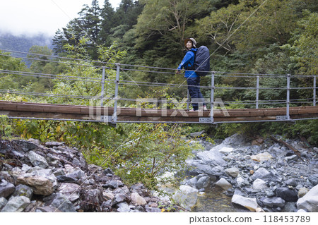 Mountain girl crossing a suspension bridge 118453789