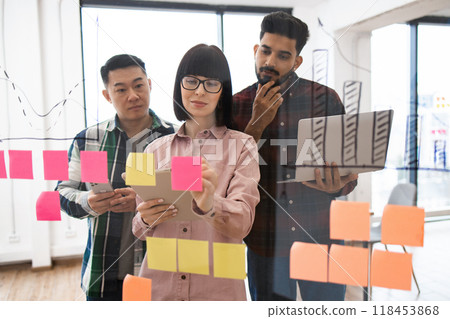 Group of colleagues brainstorming with sticky notes in office Group of colleagues brainstorming with sticky notes in office 118453868