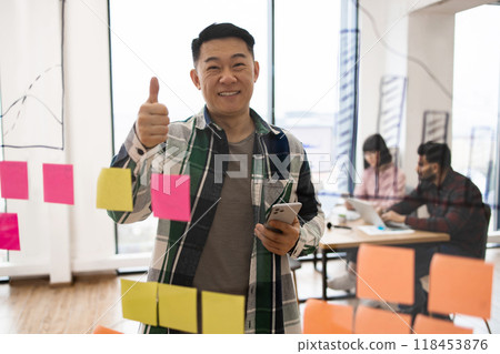Confident businessman giving thumbs up in creative office meeting Confident businessman giving thumbs up in creative office meeting 118453876
