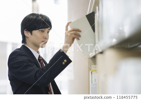 高中男孩在圖書館選擇一本書 118455775