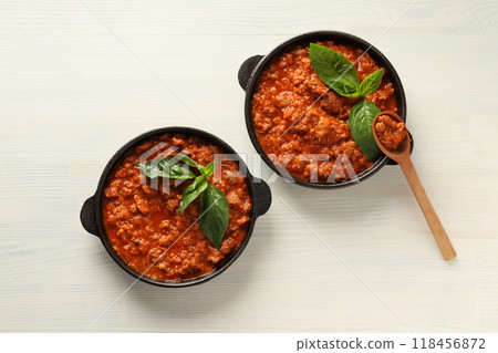 Pans with Bolognese sauce and wooden spoon on white wooden background, top view Pans with Bolognese sauce and wooden spoon on white wooden background, top view 118456872