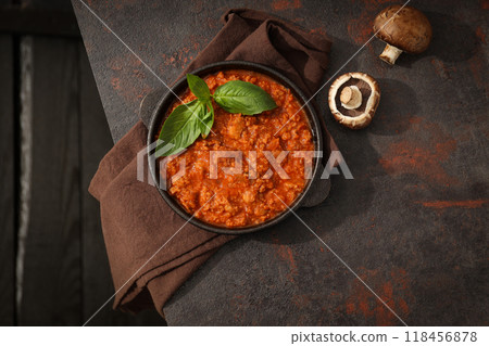 Bolognese sauce in frying pan, mushrooms and towel on dark background, top view 118456878