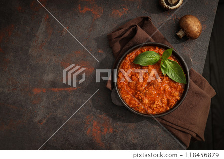 Bolognese sauce in frying pan, mushrooms and towel on dark background, space for text 118456879