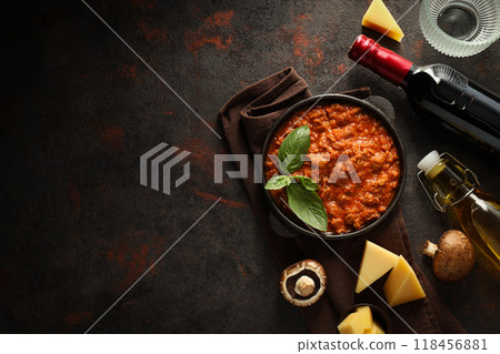 Bolognese sauce in frying pan, ingredients, glasses and bottle of wine on dark background, space for text 118456881