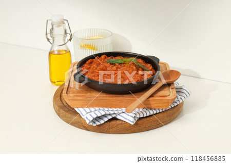 Bolognese sauce in frying pan, wooden boards, glass of water and bottle of oil on light background Bolognese sauce in frying pan, wooden boards, glass of water and bottle of oil on light background 118456885