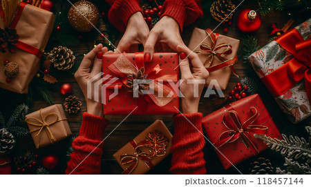 two pairs of hands in red sweaters giving and receiving christmas gift box  118457144