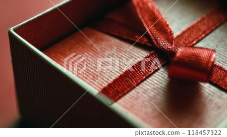 A close up of a red ribbon tied to the inside of an open box, AI 118457322