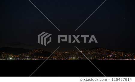 The city of Istanbul glows under the night sky, showcasing vibrant lights along the coast, creating a serene and captivating waterfront atmosphere. 118457914