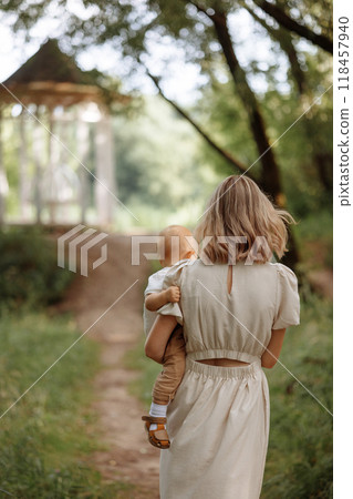 Happy woman holding a small child in her arms in the summer in a park 118457940