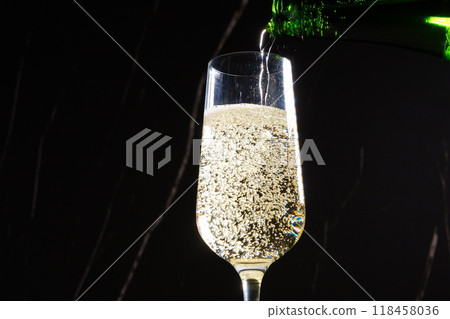 Pour champagne (sparkling wine) into a flute glass 118458036