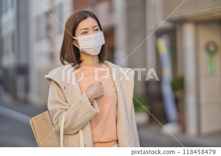 Middle-aged woman walking outdoors wearing a mask Middle-aged woman walking outdoors wearing a mask 118458479