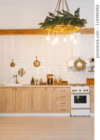 Kitchen with white stove and oven, a sink, and a large hanging wreath, decorated with Christmas lights 118460868