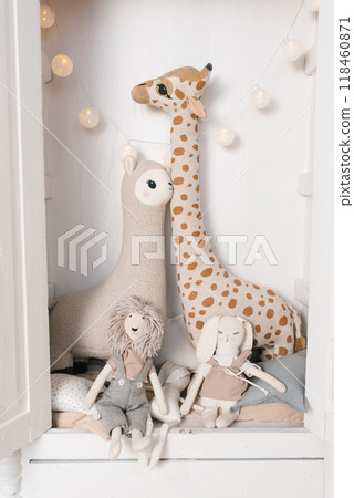 Giraffe and llama are sitting on a bed with a rabbit in children room 118460871