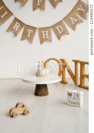 Banner hangs above a wooden cake stand with candles. Baby first birthday 118460872
