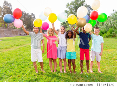 Cheerful tweenagers with colored balloons posing together in summer park Cheerful tweenagers with colored balloons posing together in summer park 118461420