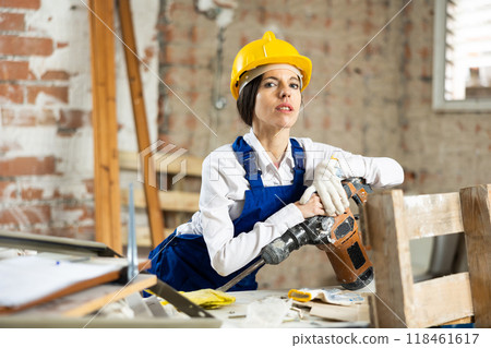 Female contractor standing with pneumatic demolition hammer at construction site Female contractor standing with pneumatic demolition hammer at construction site 118461617