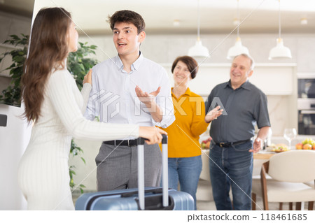 Happy young girl coming to meet boyfriend's family. Elderly mother, father and young guy joyfully greeting at door 118461685