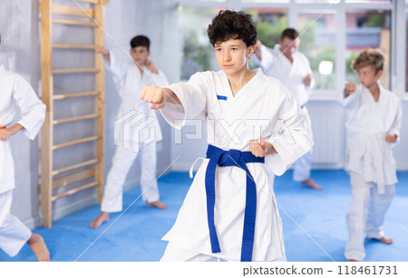 Preteen school childs together trying martial moves in karate class on tatami Preteen school childs together trying martial moves in karate class on tatami 118461731