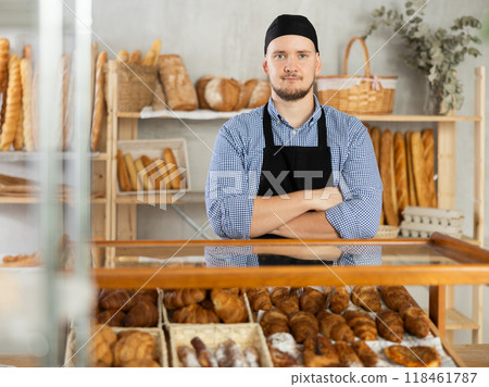 Man seller stands near window with bread and pastries at bakery 118461787