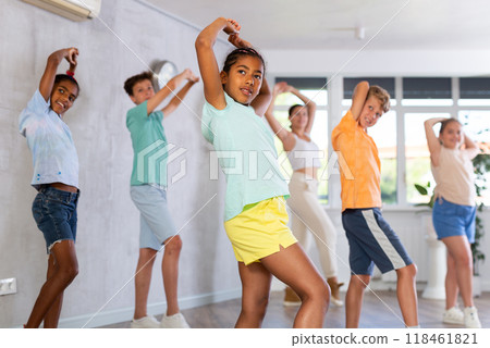 Positive juvenile girl engaged in Hip-hop dance in training room with children's group 118461821