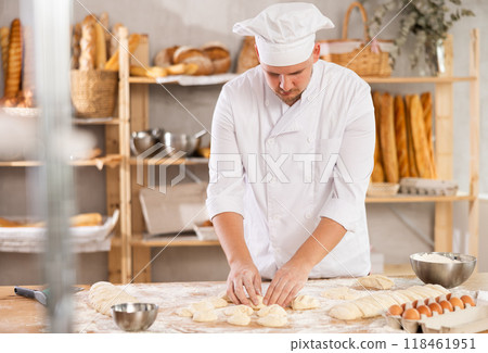 Guy works as baker in bakery, molds pies from dough, creates croissants from dough. Guy works as baker in bakery, molds pies from dough, creates croissants from dough. 118461951