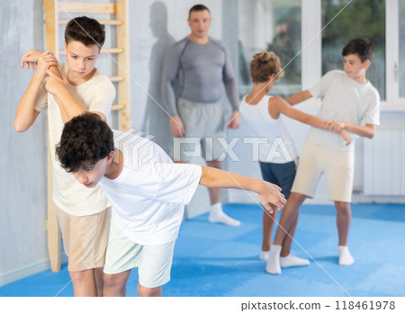 Young children working in pair mastering new self-defense moves at gym during group class Young children working in pair mastering new self-defense moves at gym during group class 118461978