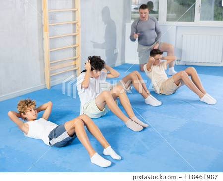 Underage boy practicing press in lying position with other attendees and trainer 118461987