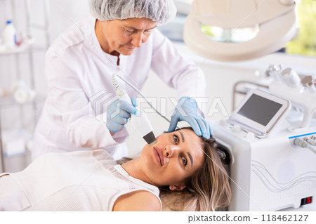 Young woman undergoing cosmetic facial treatment using ultrasonic shovel 118462127