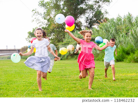 Boys and girls with balloons running thruogh field 118462232