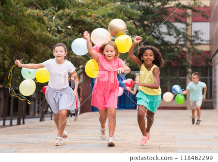 Boys and girls with balloons running thruogh streets 118462299