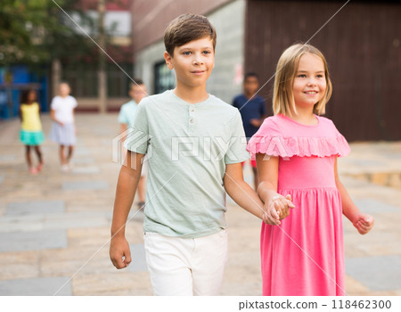 Smiling preteen girl walking with brother along city street 118462300