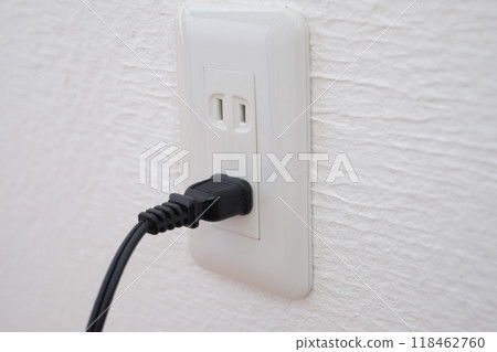 An electrical outlet and plug on a plaster wall An electrical outlet and plug on a plaster wall 118462760