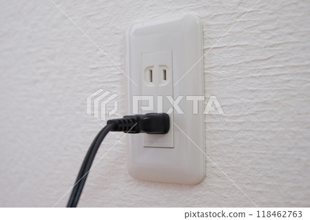 An electrical outlet and plug on a plaster wall An electrical outlet and plug on a plaster wall 118462763
