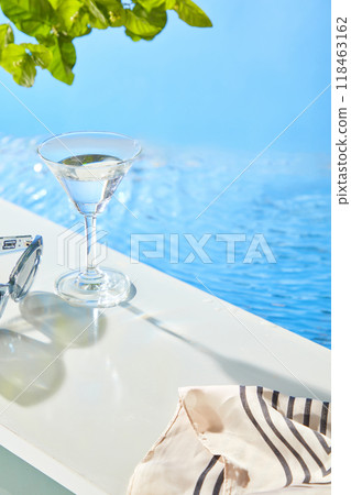A clear glass, striped linen cloth, and sunglasses are displayed alongside a pool, leaving space for product display., creating a perfect backdrop for promoting beauty products. A clear glass, striped linen cloth, and sunglasses are displayed alongside a pool, leaving space for product display., creating a perfect backdrop for promoting beauty products. 118463162