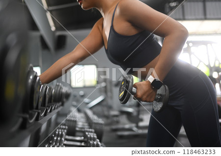 Fit strong young woman focusing on a weightlifting exercise in gym Fit strong young woman focusing on a weightlifting exercise in gym 118463233