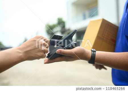 Unrecognizable man making contactless payment with a credit card while receiving parcel box from delivery man Unrecognizable man making contactless payment with a credit card while receiving parcel box from delivery man 118463266