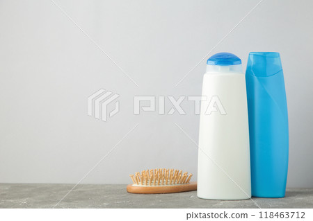 White and blue shampoo bottle with comb on grey background 118463712