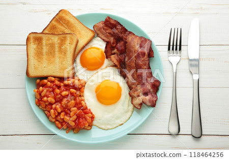 Traditional full English breakfast - fried eggs, beans, bacon and toast on white table. 118464256