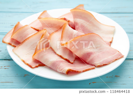 Fresh raw slices bacon on plate on blue wooden background. 118464418