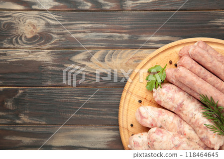 Raw sausage on cutting board on brown wooden background. Top view Raw sausage on cutting board on brown wooden background. Top view 118464645