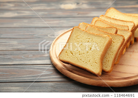 Pile of toasted bread slices on cutting board on brown background. 118464691