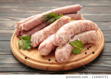 Raw sausage on cutting board on brown background. Top view Raw sausage on cutting board on brown background. Top view 118464731