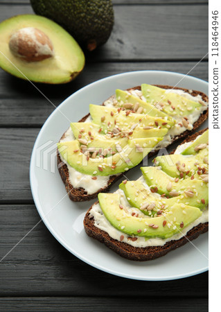 Avocado sandwich on dark rye bread made with fresh sliced avocados on dark background. 118464946
