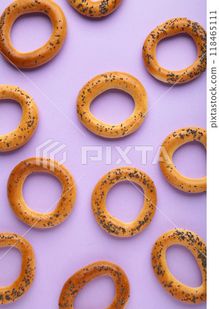 Whole bagel with poppy seeds on purple background. Vertical photo 118465111