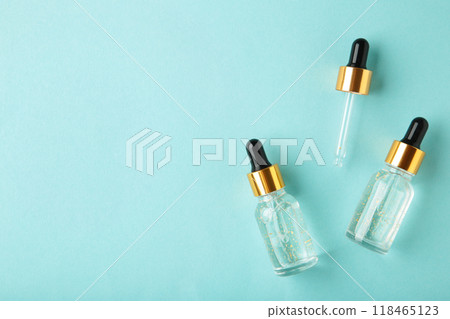 A glass bottles with a pipette with oil, serum on blue background with copy space. Flatlay A glass bottles with a pipette with oil, serum on blue background with copy space. Flatlay 118465123