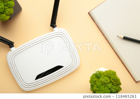 Wireless Wi-Fi router on beige background with notebook on beige Wireless Wi-Fi router on beige background with notebook on beige 118465261