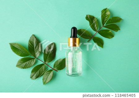 Natural skincare bottle container and organic green leaf , flowers ingredients with the laboratory glassware on mint background. Essential oil Natural skincare bottle container and organic green leaf , flowers ingredients with the laboratory glassware on mint background. Essential oil 118465405