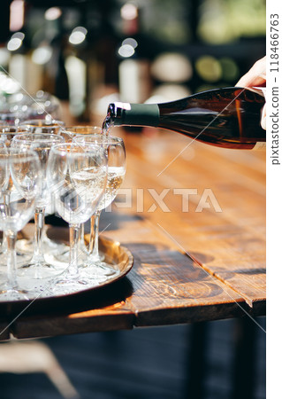 A waiter pours wine into glasses at an outdoor buffet. A waiter pours wine into glasses at an outdoor buffet. 118466763
