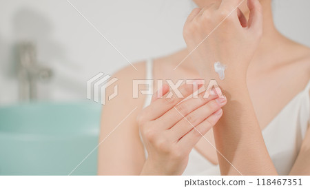 The advertising template photo for skincare product, a female with white dress is showing white cream texture on the back of hand. Front view on blurred bathroom background, copy space for adding text The advertising template photo for skincare product, a female with white dress is showing white cream texture on the back of hand. Front view on blurred bathroom background, copy space for adding text 118467351